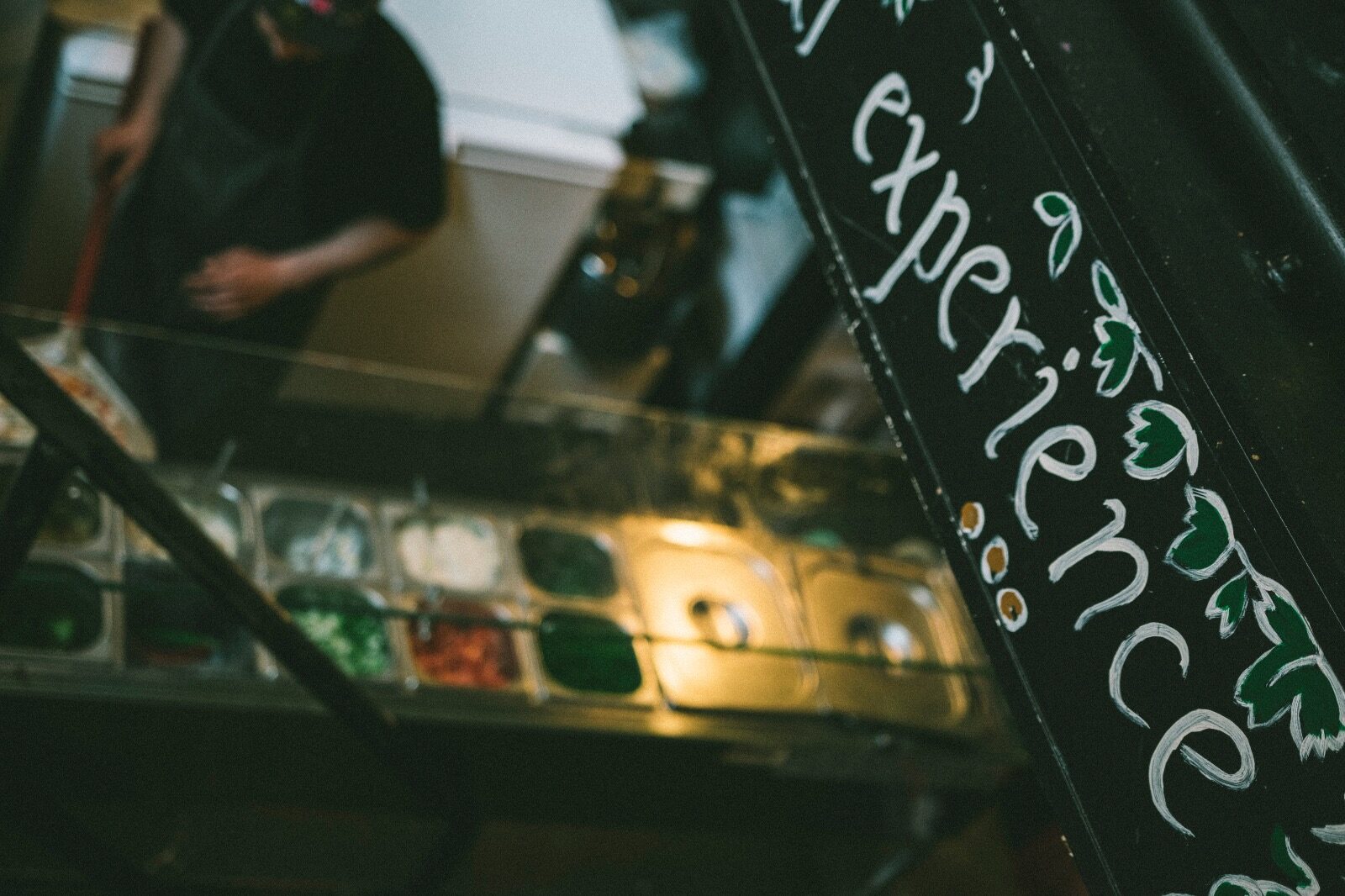 De open keuken met verse mezze in de koeling en een krijtbord met 'experience'
